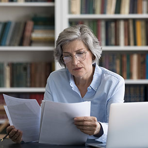 A woman doing paperwork. Links to Gifts by Estate Note